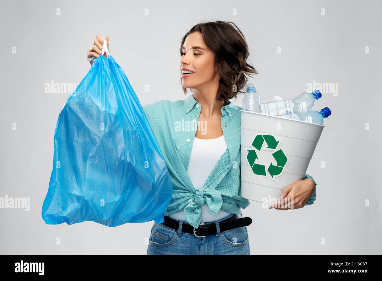 Lächelnde Frau, die Plastikmüll und Müllbeutel sortiert Stockfoto