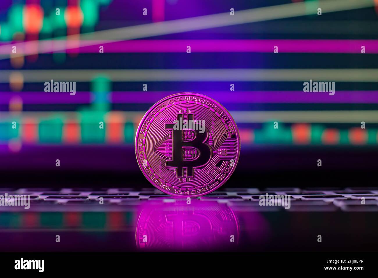 Bitcoin auf dem Hintergrund einer Grafik auf einem Laptop in Neonlicht. Kryptowährung. Stockfoto