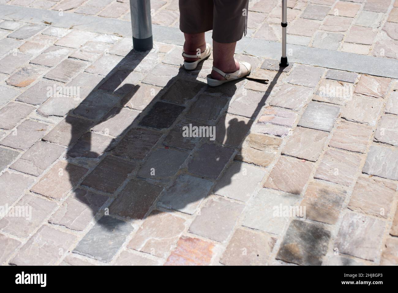 Schatten und Beine einer älteren Frau mit Gehhilfe Stockfoto