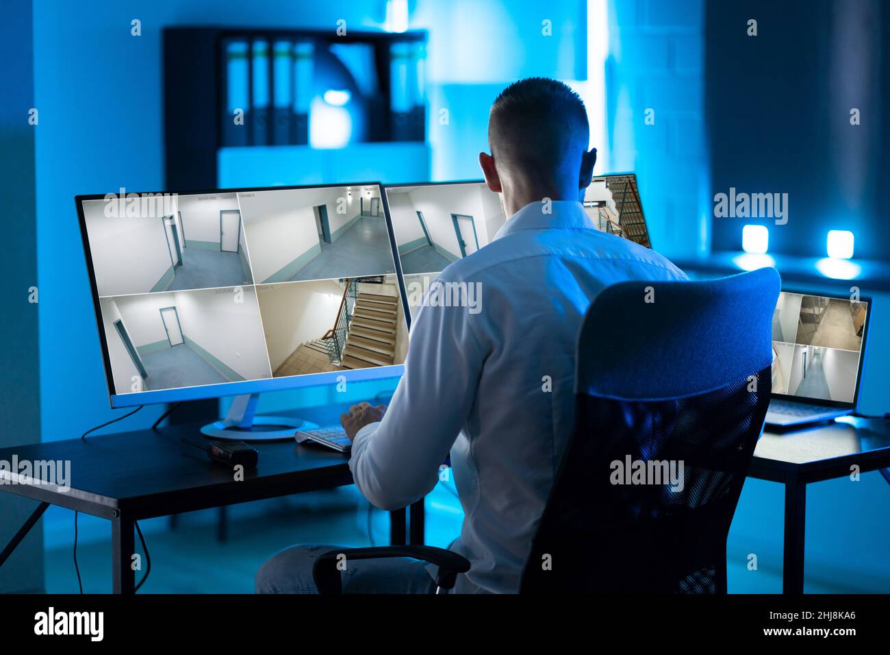 Der Bediener des Sicherheitssystems sieht sich CCTV-Aufnahmen am Schreibtisch an Büro Stockfoto