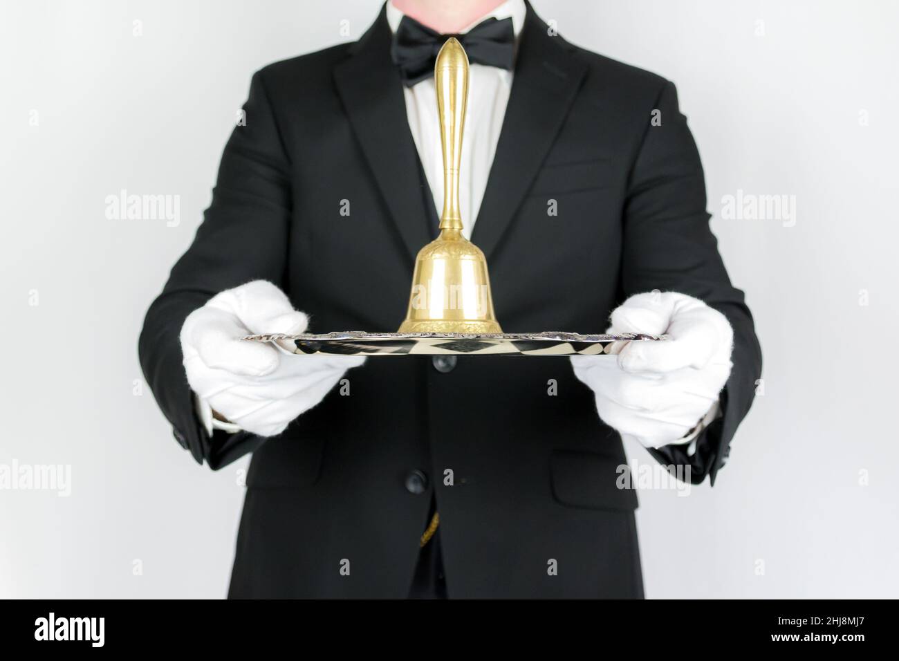 Porträt eines Butlers oder Kellers in formeller Kleidung mit Goldglocke auf silbernem Serviertablett. Dienstleistungsbranche und professionelle Gastgewerbe. Stockfoto