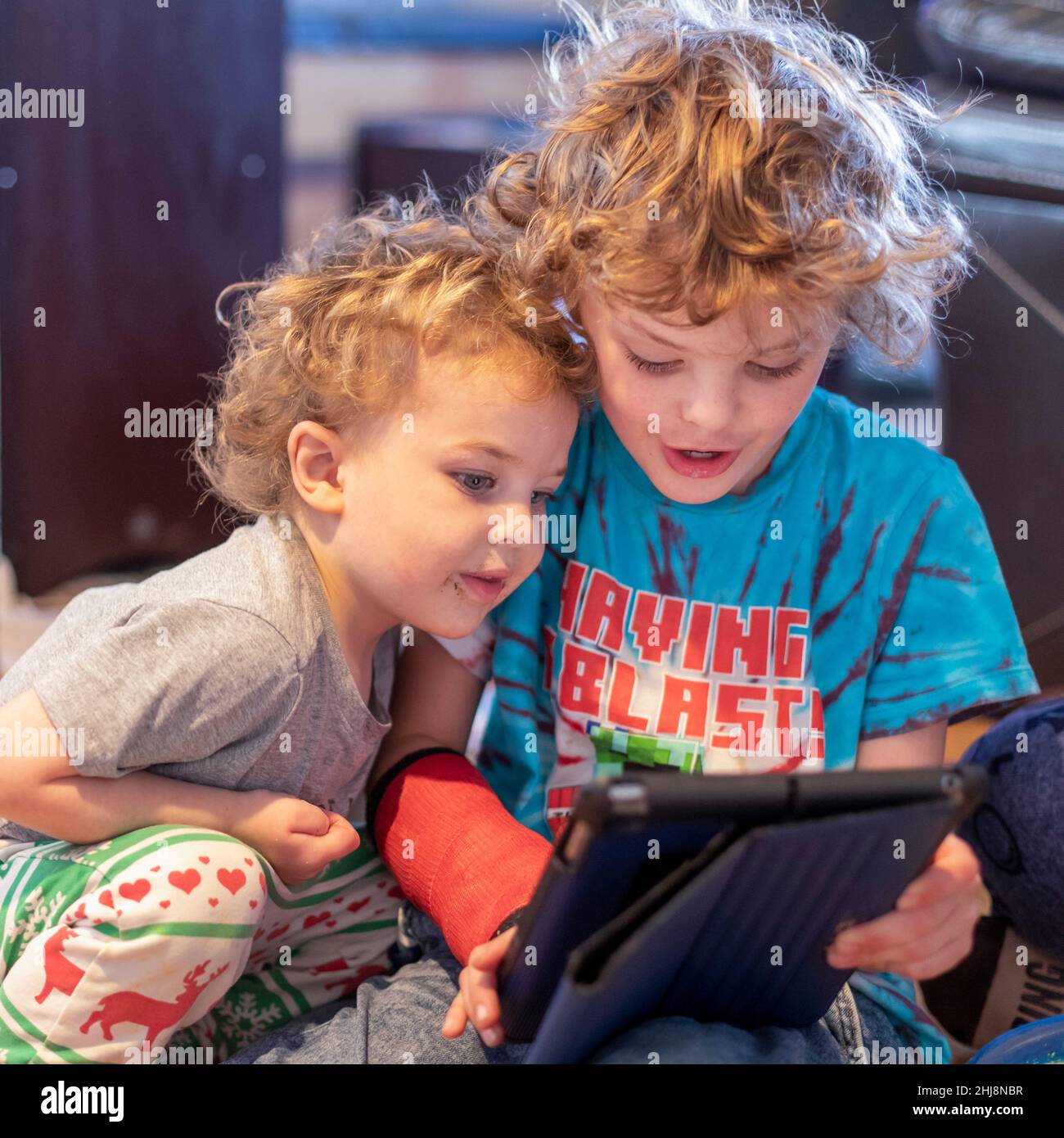 Adam Hjermstad Jr., 7 (rechts), und sein Bruder Hendrix Hjermstad, 3, schauen sich Inhalte auf einem iPad an. Stockfoto