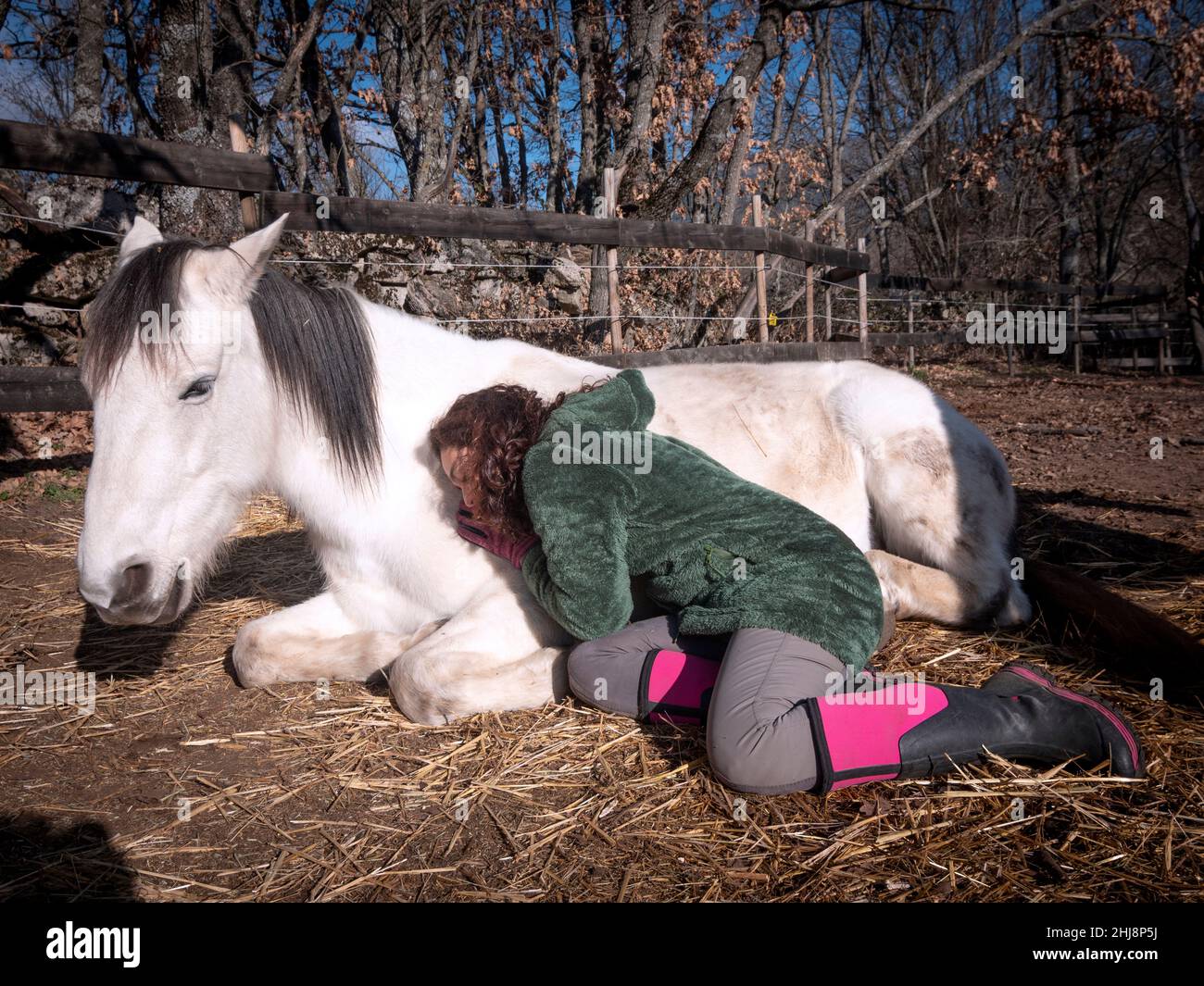 Weibchen in grüner Polar Fleece Jacke, die Energie heilende Arbeit zu einem weißen Pony tut. Stockfoto