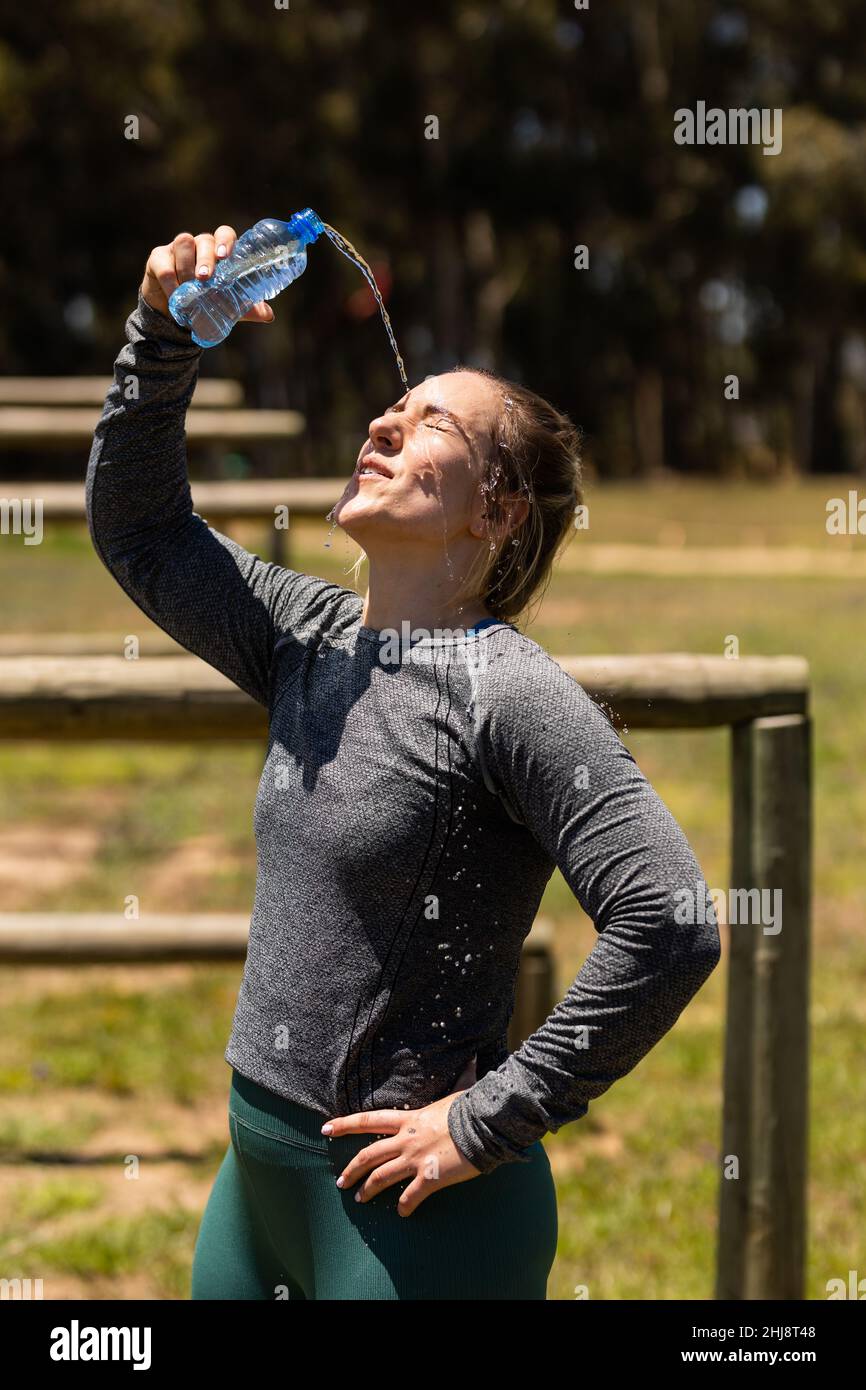 Weibliche Kaukasierin passt Frau, die im Bootcamp Wasser über ihr Gesicht gießt Stockfoto