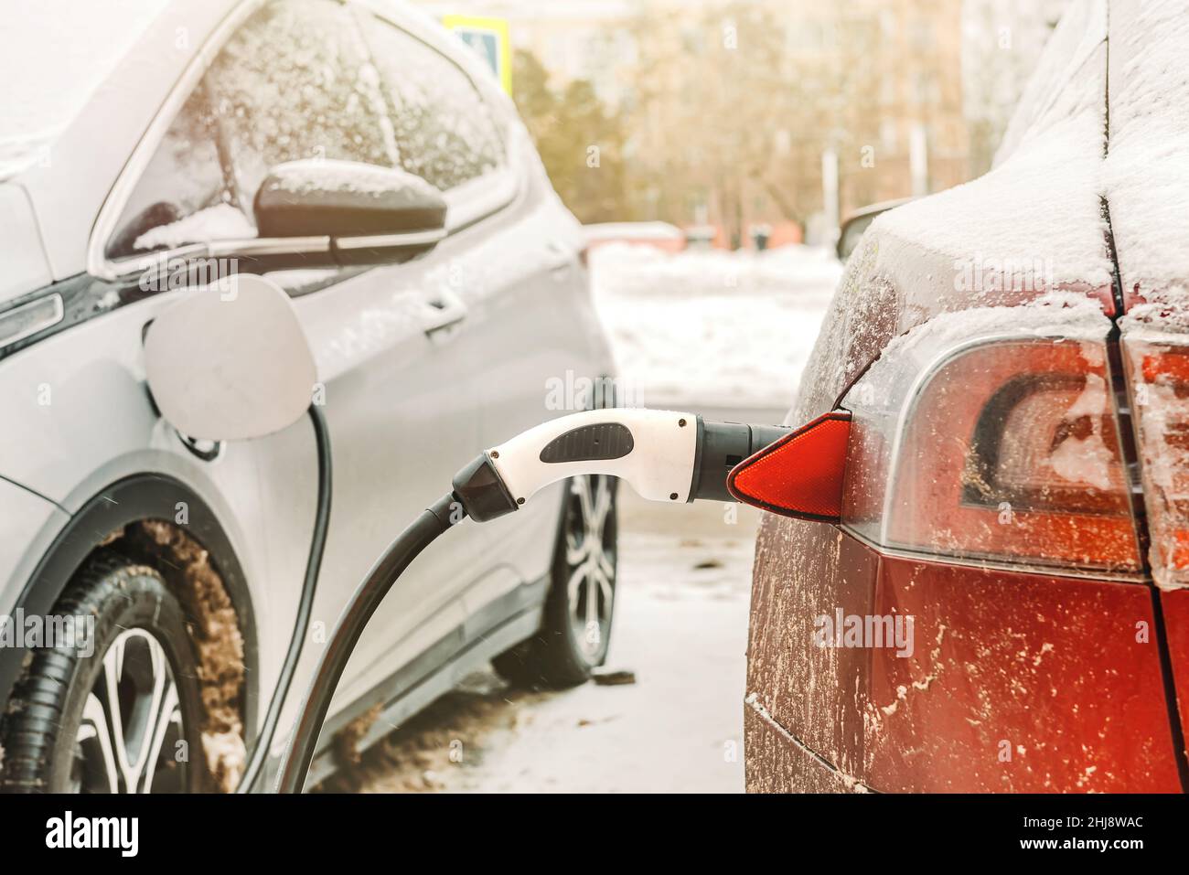Im Winter wird ein Elektroauto von einer elektrischen Ladestation geladen. Umweltfreundlicher Verkehr. Transport mit Batterien Stockfoto
