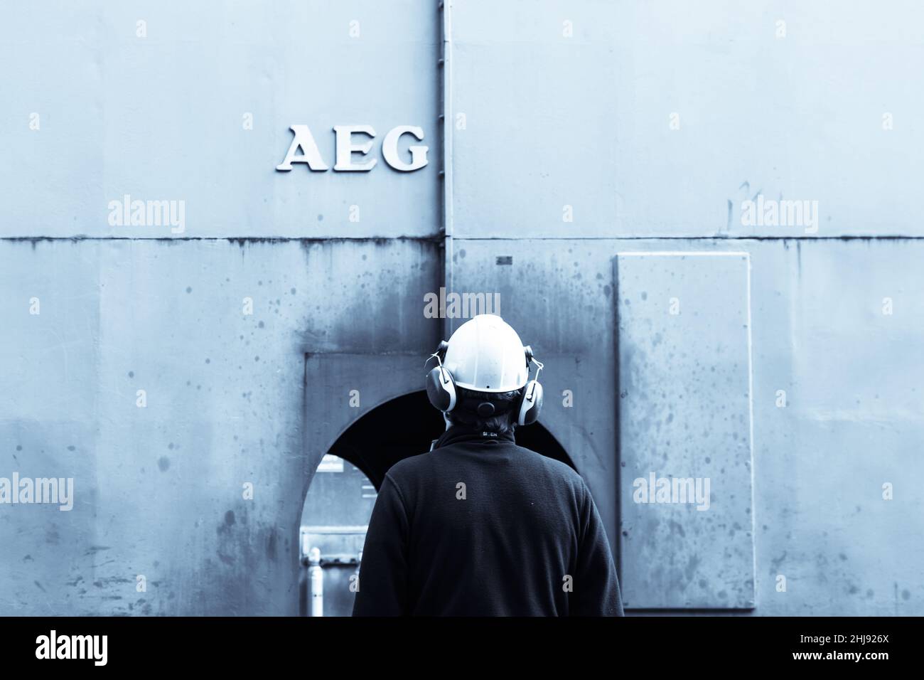Ingenieur mit weißem Helm, der das Gehäuse eines AEG Kompressionsmotors betrachtet Stockfoto