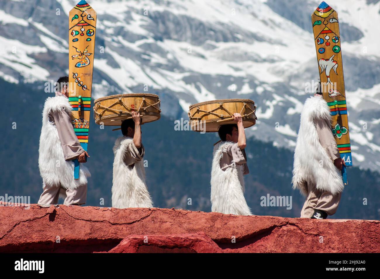 Die ethnische Minderheit der Naxi in ihren traditionellen Kostümen; Szene aus einer Performance mit dem Jadedrachen-Schneeberg im Hintergrund Stockfoto