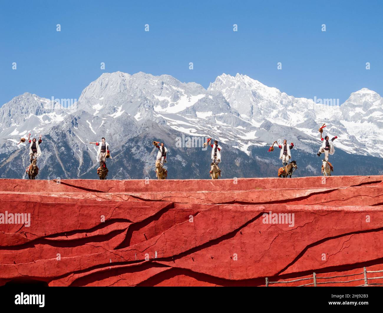 Die ethnische Minderheit der Naxi in ihren traditionellen Kostümen; Szene aus einer Performance mit dem Jadedrachen-Schneeberg im Hintergrund Stockfoto