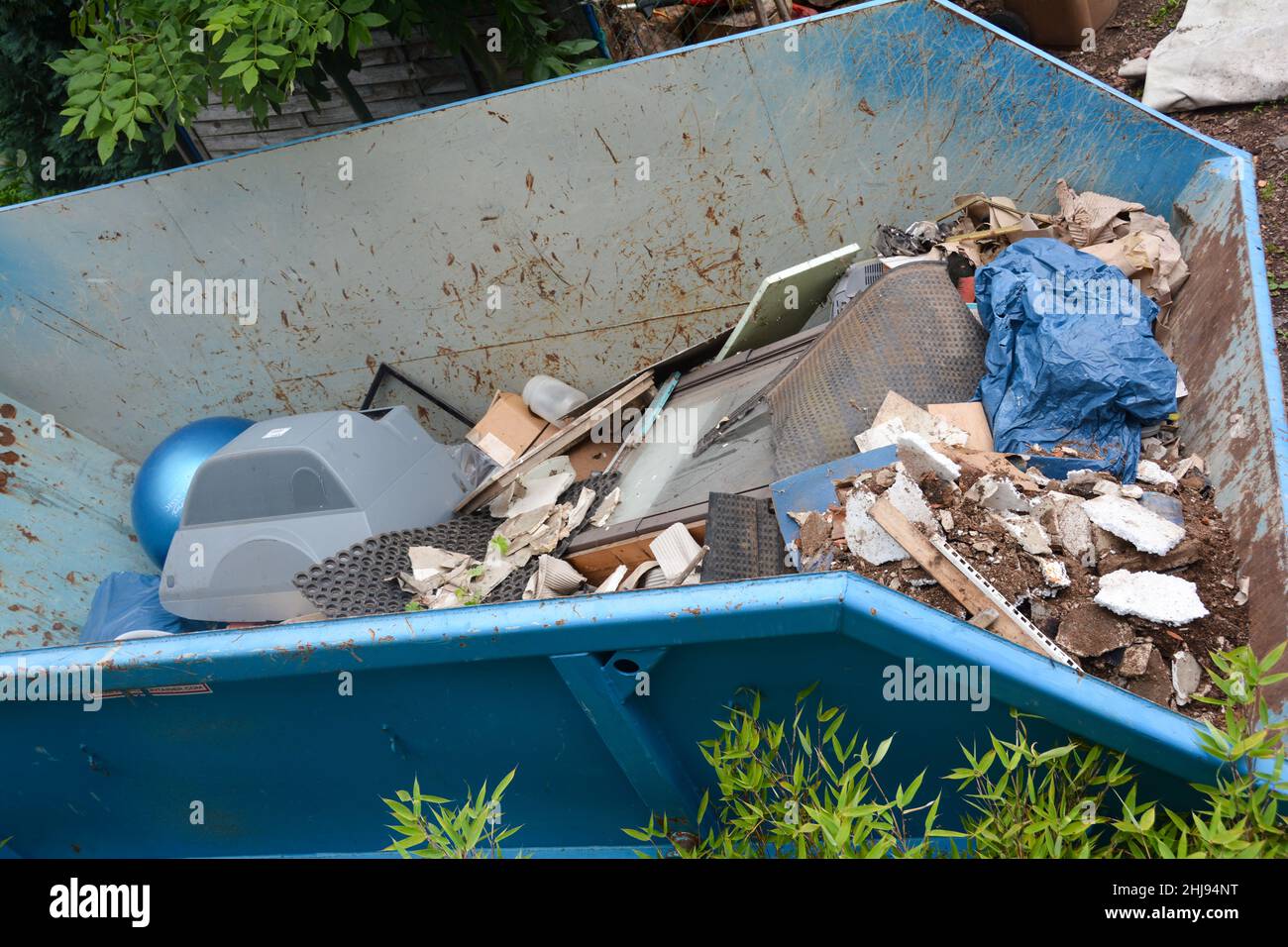 Ein großer blauer Müllcontainer mit sperrigen Abfällen Stockfoto