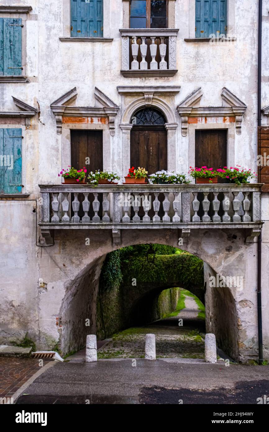 Die Fassade eines alten Hauses mit Fenstern, Fensterläden, Balkon und Tunneldurchgang. Stockfoto