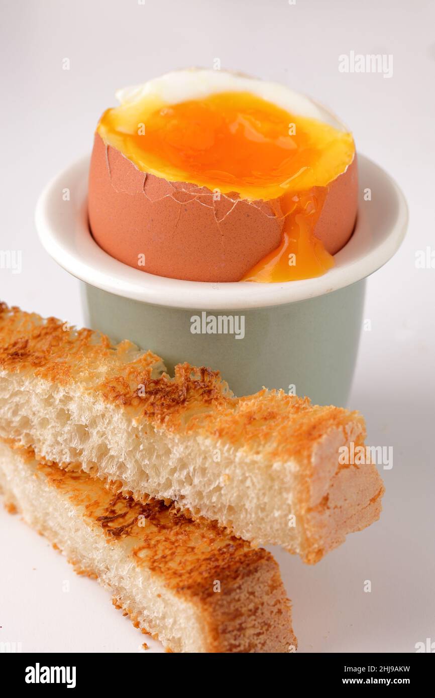 Ein frisches, weich gekochtes Ei mit laufendes Eigelb in einer Eierschale mit Toastsoldaten Stockfoto