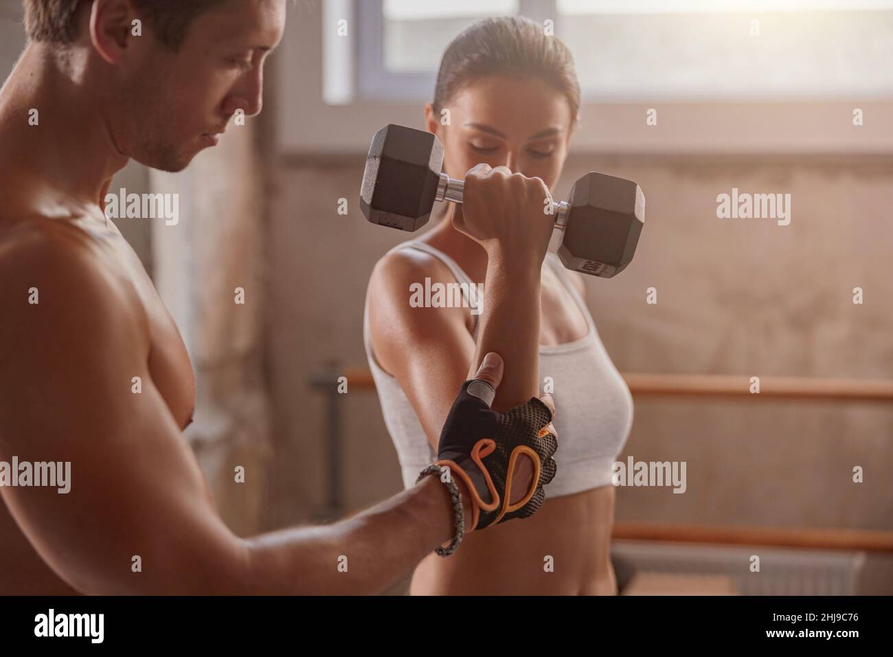 Muskulöser Mann im Fitnessstudio mit einer athletischen Frau, die Sportübungen durchführt Stockfoto