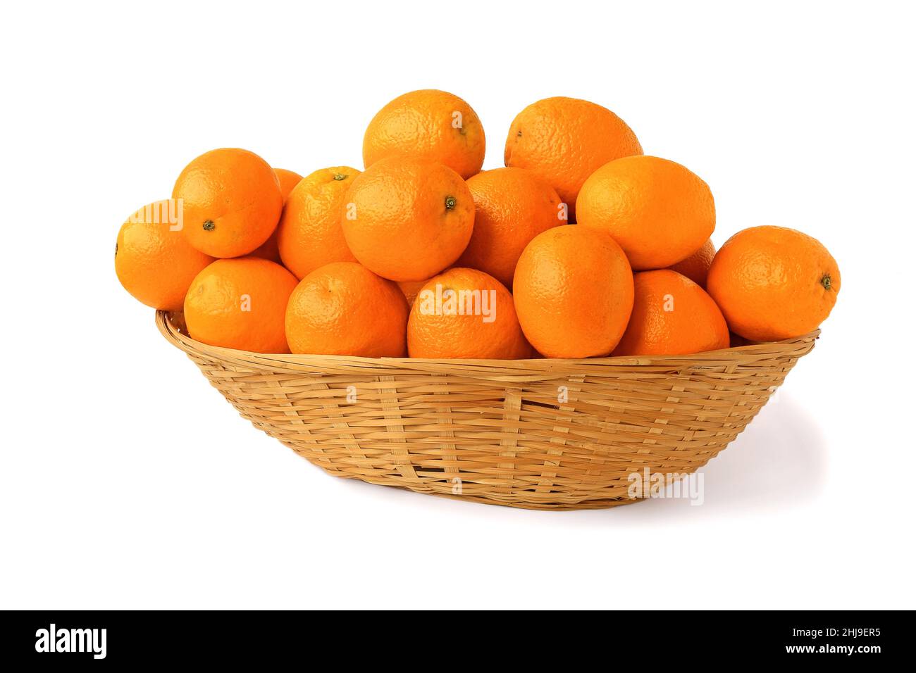 Orangen in einem großen Korbkorb isoliert auf weißem Hintergrund Stockfoto