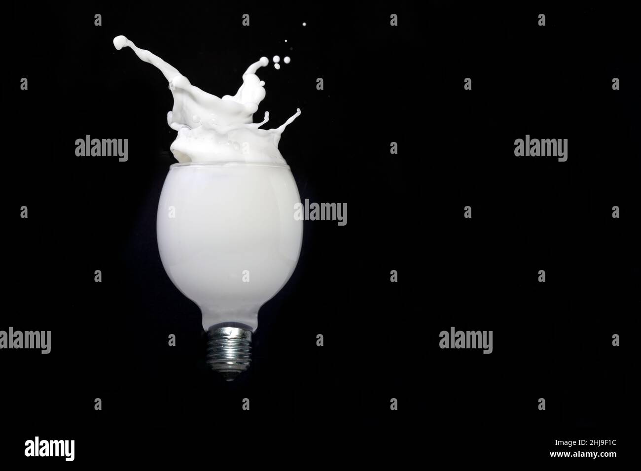 Milchspritzer in einer Glühbirne, isoliert auf Schwarz Stockfoto