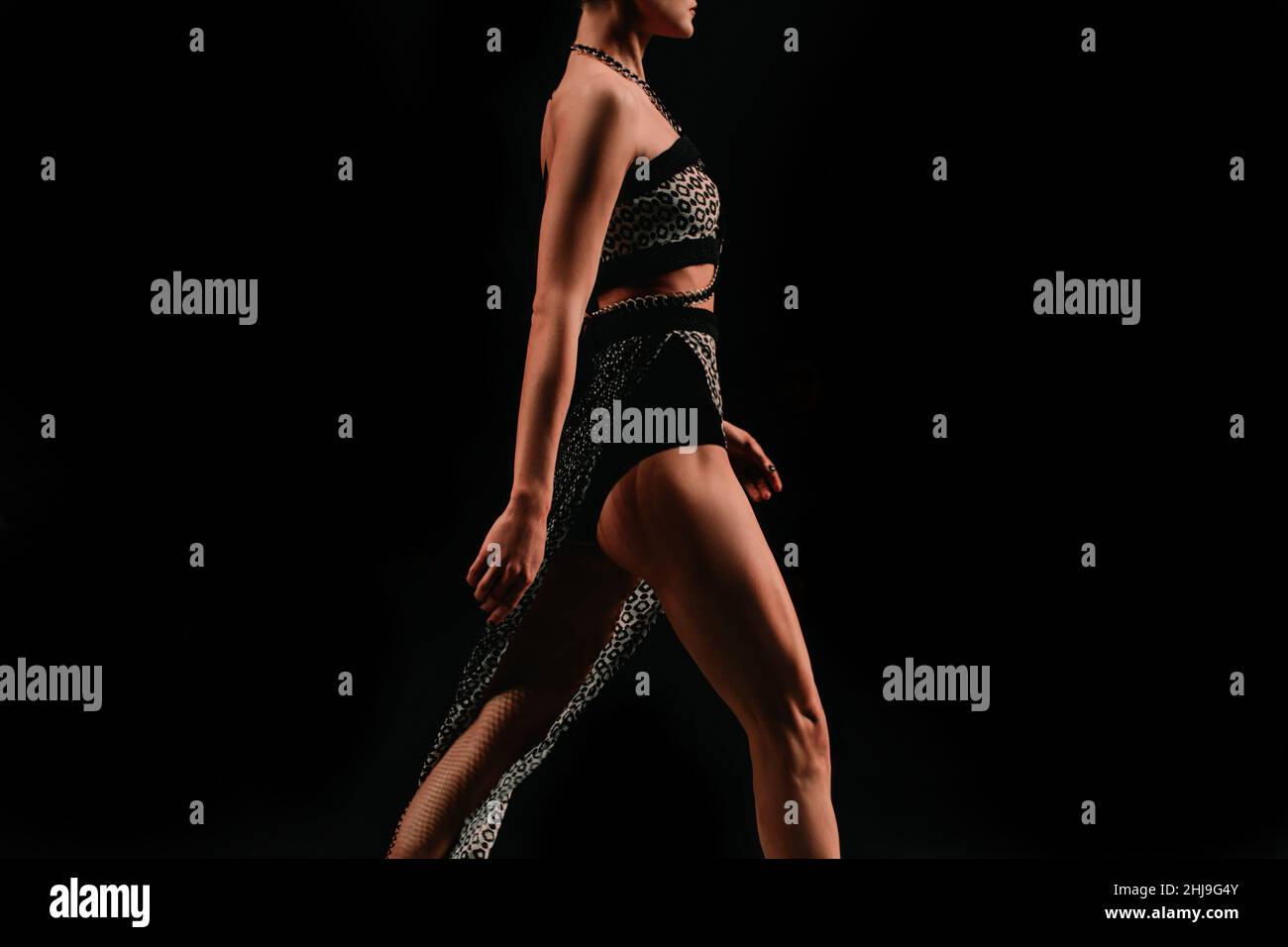 Weibliche Figur in einem Crop Top und Rock zu Fuß auf einem schwarzen Hintergrund gekleidet. Modisch ausgefallene Details Stockfoto