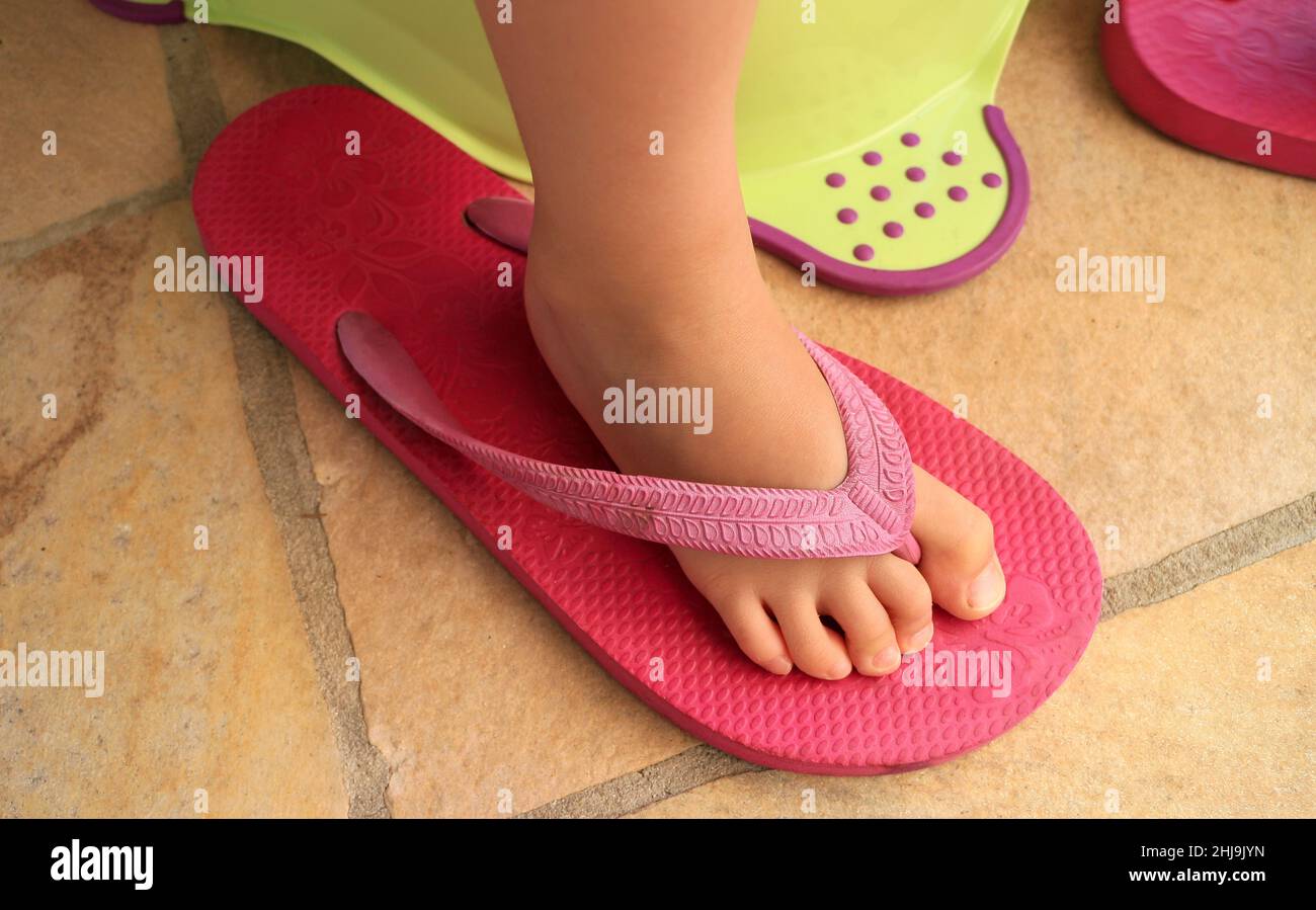Fuß eines Kindes in einer rosa Flip-Flop-Sandale eines Erwachsenen Stockfoto