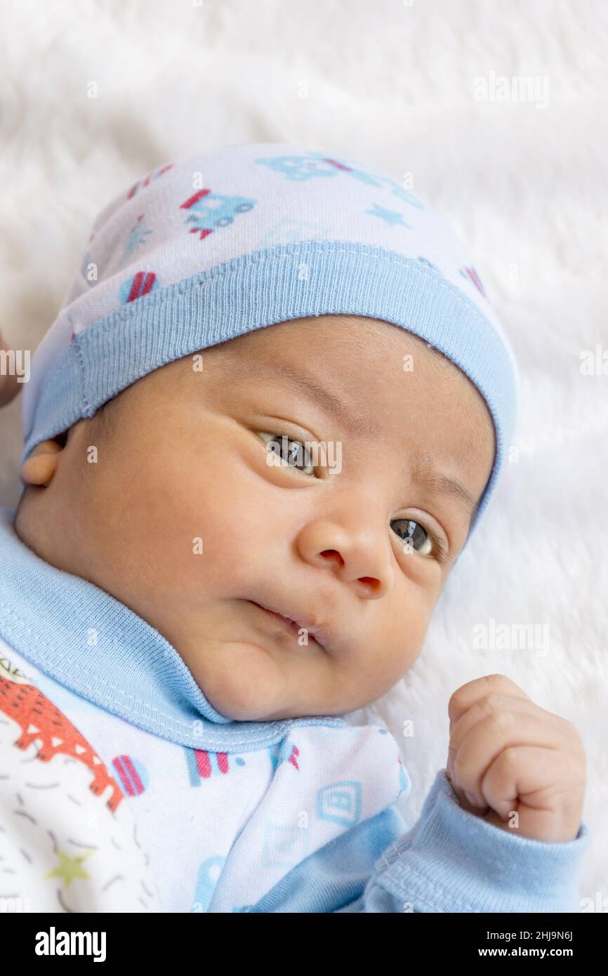 Entzückendes lateinisches Baby, das sich hinlegt, einen Hut und Bettwäsche trägt, neugeborener Lebensstil, neues Leben und die Pflege des Säuglings mit Liebe im Studio Stockfoto