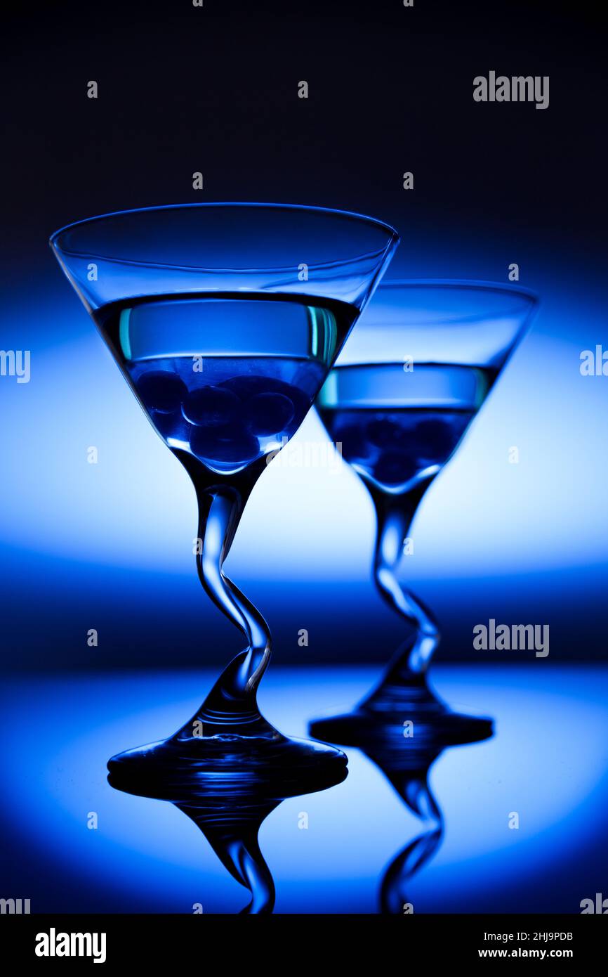 Zwei alkoholische Heidelbeer-martini-Getränke stehen in einer blauen Nachteinstellung. Stockfoto