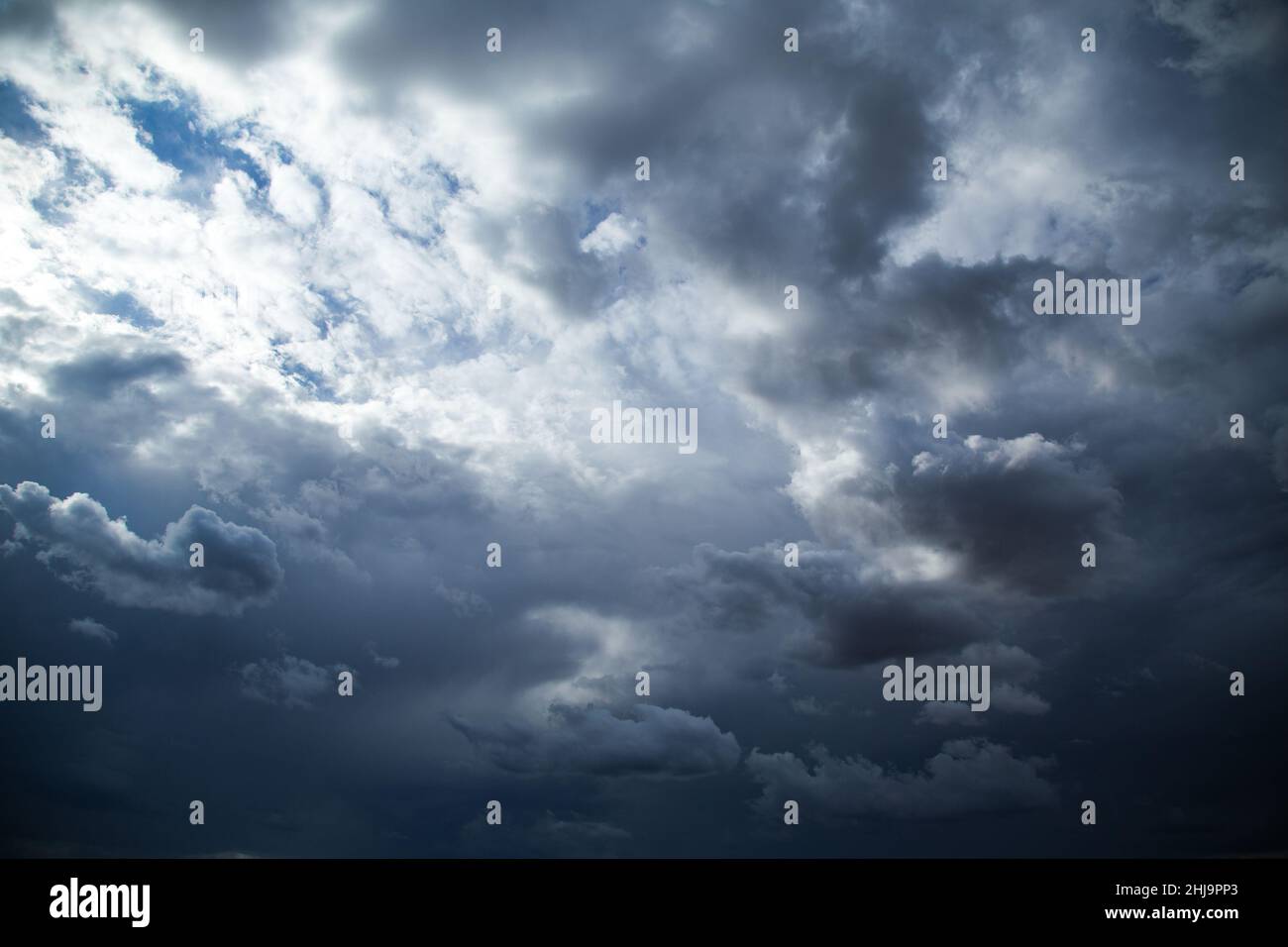 Dramatische, dunkle Regenwolken am Himmel mit einer kleinen Sonneneinstrahlung. Stockfoto