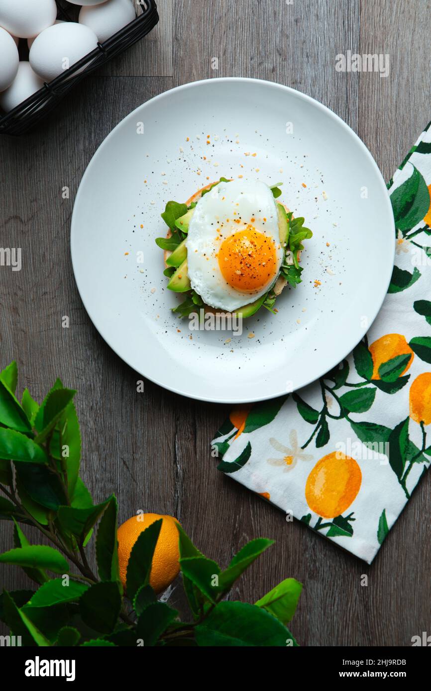 Frisches und gesundes Ei, Avocado und Rucola-Toast bereit zum Essen auf einer modernen Holzplatte. Stockfoto