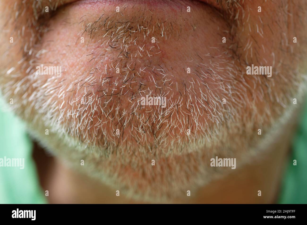Ein paar Tage Bartwuchs oder Stoppeln sind auf dem Kinn eines Mannes mittleren Alters abgebildet. Stockfoto