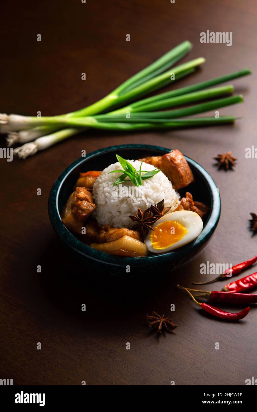 Asiatische Schüssel mit süßem Schweinefleisch, Ei, Reiskugel, grünen Zwiebeln, roten Chilischoten und Sternanis. Stockfoto