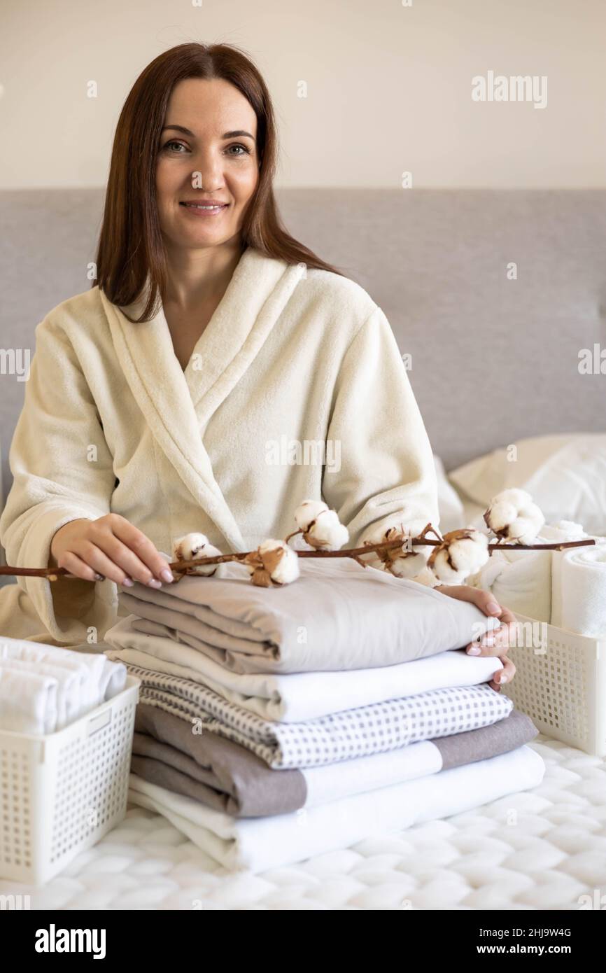 Gut gepflegte Frau Hände halten die Baumwollzweig mit Haufen Von gefalteten Bettlaken und Decken Stockfoto