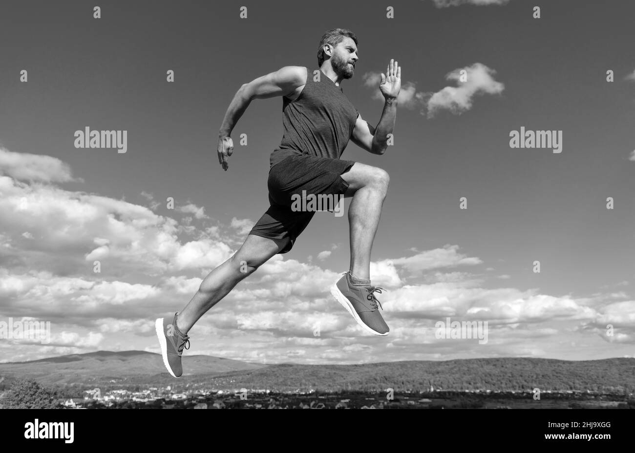 Energischer Mann Athlet mit muskulösen Körper laufen in Sportswear im Freien auf Himmel Hintergrund, Joggen Stockfoto