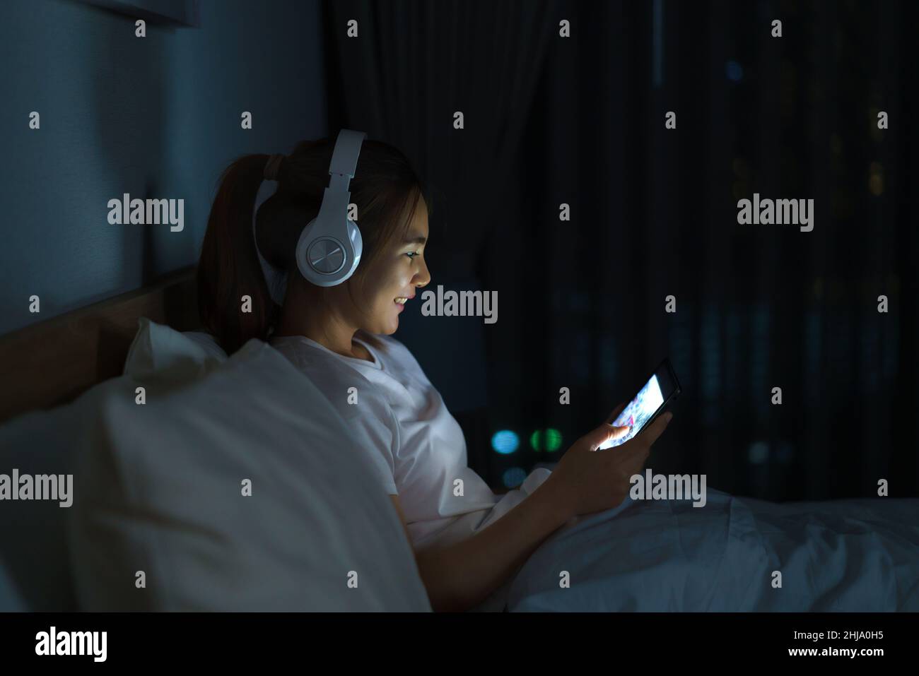 Asiatische mobile süchtig Frau mit digitalen Tablet im Internet surfen für Filme oder virtuelle Meeting-Video-Anruf online mit Freund auf dem Bett Stockfoto