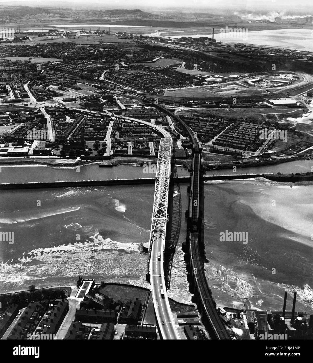 Luftaufnahme der neuen Runcorn - Widnes Brücke über den Fluss Mersey und Manchester Ship Canal. Rechts auf dem Bild ist die Brücke zu sehen, die sie ersetzen sollte, die Widnes-Runcorn Transporter Bridge. Die Brücke wurde am 21st. Juli 1961 von Prinzessin Alexandra offiziell eröffnet. Ca. 1962. Stockfoto