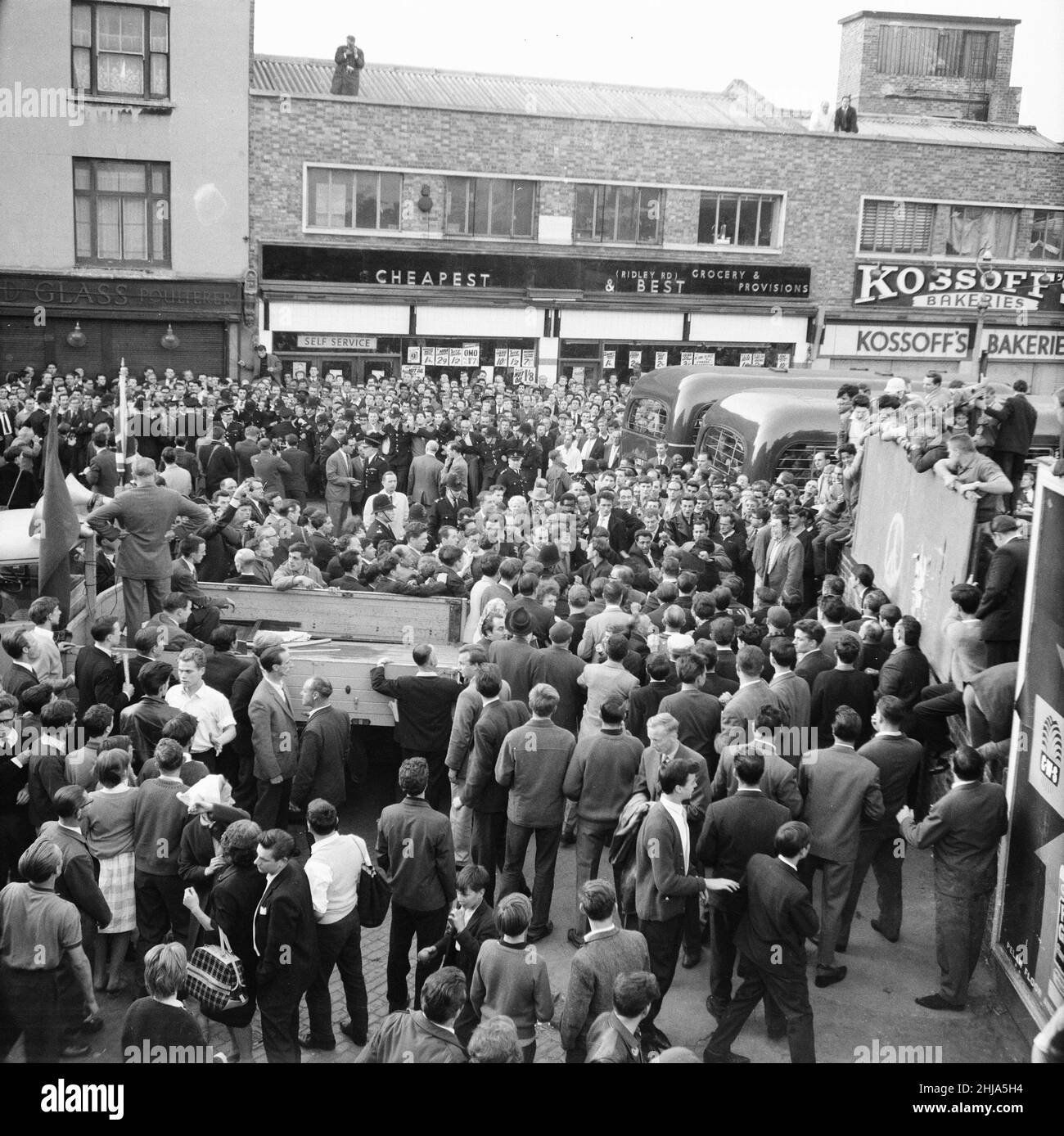 Ridley Road, London, Dienstag, 31st. Juli 1962. Eine große Menge versammelt sich im East End, um eine Kundgebung des ehemaligen faschistischen Führers Sir Oswald Mosley und seiner antisemitischen Blackshirt-Gruppe zu stören, die eine Kundgebung im Londoner East End geplant hatte. Mosley und seine Gruppe wurden angegriffen und zu Boden geschlagen, sobald sein Treffen in der Ridley Road, Dalston, eröffnet wurde. Die Polizei schloss das Treffen innerhalb der ersten drei Minuten ab und verhaftete 54 Personen, darunter Sir Oswalds Sohn Max. Stockfoto