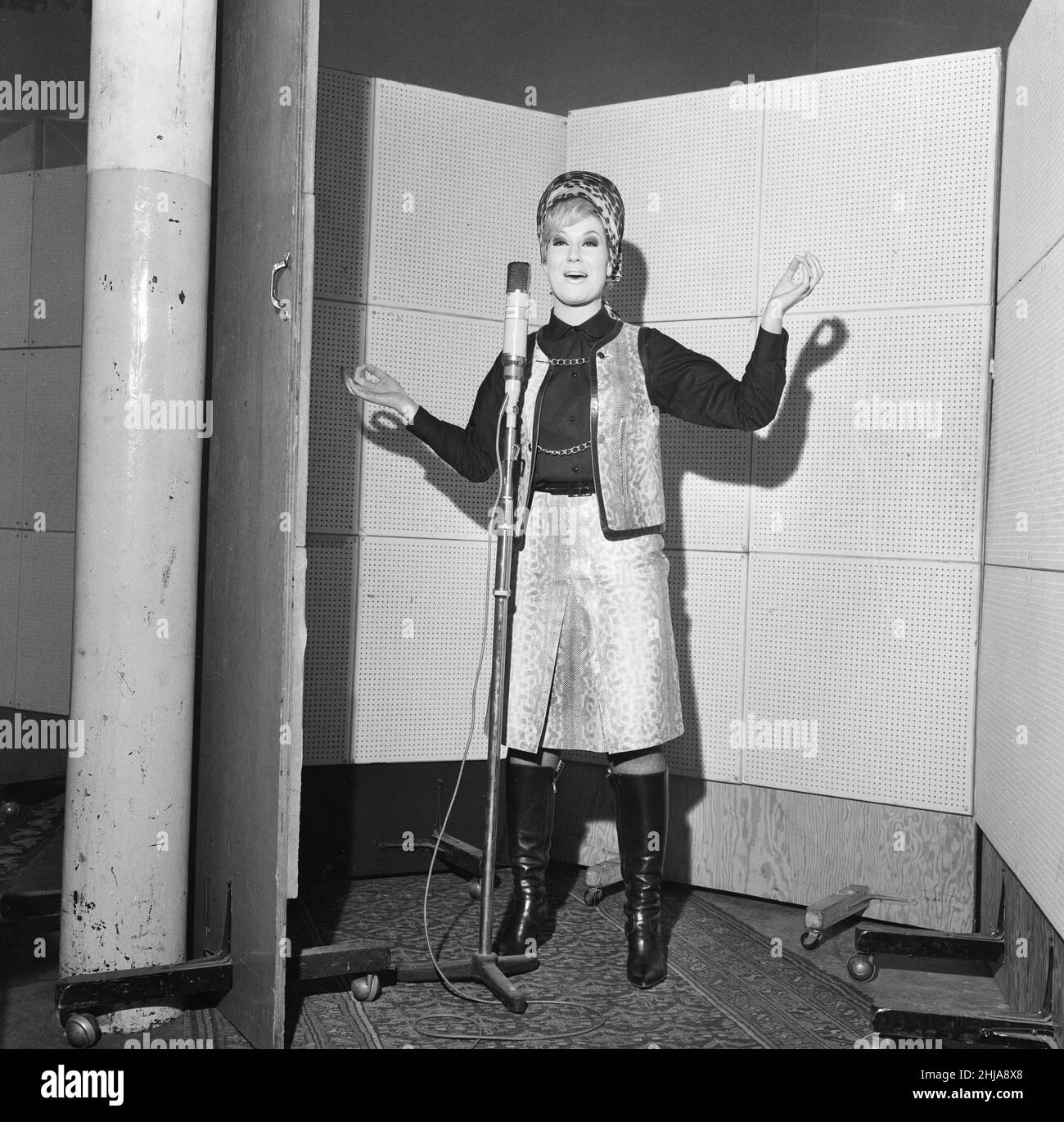 Dusty Springfield, beliebte englische Sängerin, nahm in den Phillips Recording Studios in London einen Song auf, der ihre neue Single werden könnte, und begann auch mit der Arbeit an ihrem neuen Album. Das Outfit, das Dusty für ihr Aufnahmedatum trug, war ein zweiteiliger Python - Skin Suit mit einem schwarzen Hemd und schwarzen Lederstiefeln. Ihre berühmte Frisur wurde unter einem Turban versteckt, da sie es nicht geschafft hat, den Friseur zu besuchen. Bild aufgenommen am 21st. Januar 1964 Stockfoto