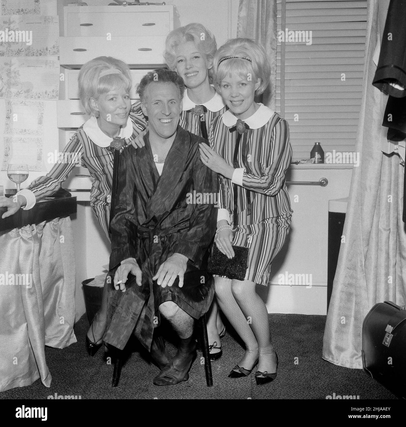 Bruce Forsyth mit den Beverly Sisters. Aufgenommen beim Talk of the Town, London, wo Bruce seine Eröffnungsnacht hatte. Die Beverley Sisters sind hier von links nach rechts als Babs, Joy und Teddie beschrift. Sie sind ein britisches weibliches Vokal- und Light-Entertainment-Trio, das in den Jahren 1950s und 1960s am beliebtesten war. Die älteste Schwester Joy und die Zwillinge, Teddie und Babs, sind lose dem Vorbild ihrer amerikanischen Pendants, den Andrews Sisters, nachempfunden. Aufgenommen am 5th. Mai 1964 Bruce Forsyth mit den Beverly Sisters. Aufgenommen beim Talk of the Town, London, wo Bruce seine Eröffnungsnacht hatte. Stockfoto