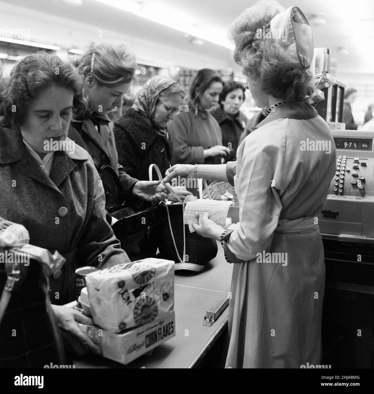 Shopper, Fine Fare Supermarket, Wilton, London, 29th. Oktober 1963. Sammeln Sie Green Shield Briefmarken an der Kasse, nachdem Sie für Waren bezahlt haben. Green Shield Stamps ist ein britisches Verkaufsförderungsprogramm, das Käufer mit Briefmarken belohnt, die eingelöst werden können und zum Kauf von Geschenken aus einem Katalog oder einem angeschlossenen Einzelhändler verwendet werden. Stockfoto