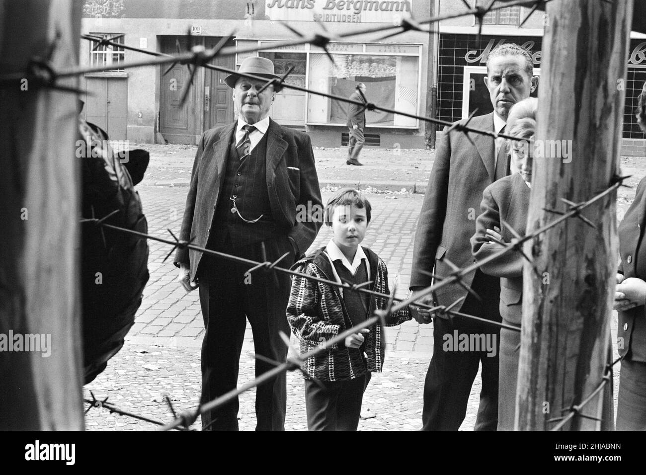 Szenen in Berlin, drei Jahre nach Beginn der Arbeiten am Bau der Berliner Mauer, die Ost und West trennt. Berliner Bürger blicken durch den Stacheldrahtzaun zu ihren Nachbarn auf der anderen Seite. 25th. Oktober 1964. Stockfoto