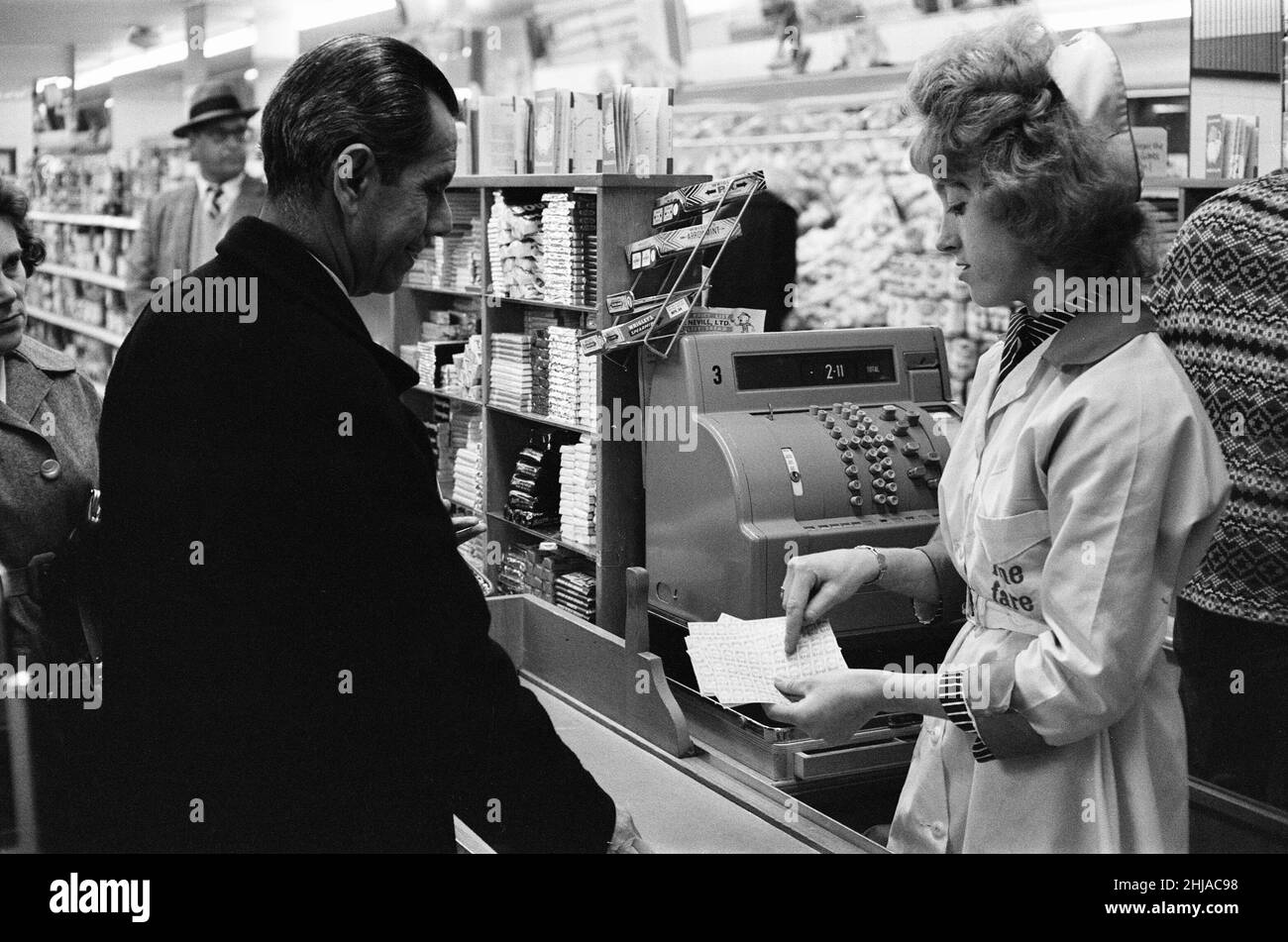 Shopper, Fine Fare Supermarket, Wilton, London, 29th. Oktober 1963. Sammeln Sie Green Shield Briefmarken an der Kasse, nachdem Sie für Waren bezahlt haben. Green Shield Stamps ist ein britisches Verkaufsförderungsprogramm, das Käufer mit Briefmarken belohnt, die eingelöst werden können und zum Kauf von Geschenken aus einem Katalog oder einem angeschlossenen Einzelhändler verwendet werden. Stockfoto