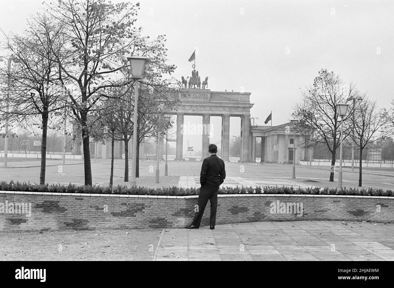 Szenen in Berlin, drei Jahre nach Beginn der Arbeiten am Bau der Berliner Mauer, die Ost und West trennt. Ein Bürger mit Blick auf das Brandenburger Tor am Pariser Platz. 25th. Oktober 1964. Stockfoto