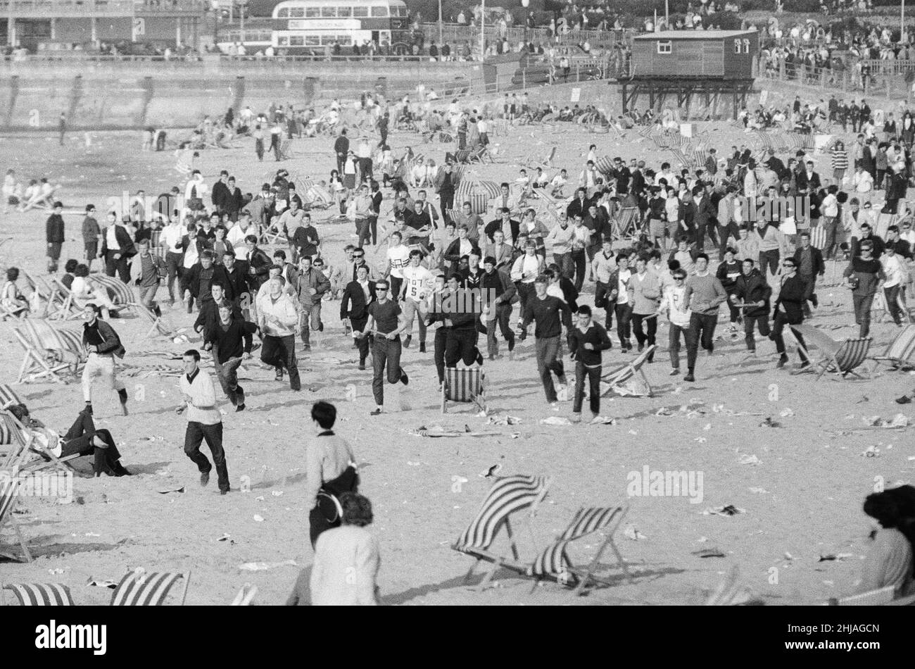 Mods gegen Rockers. Bild zeigt die Szene in Margate, North East Kent im Mai 1964. Mods laufen über den Strand und stören die Urlauber, während sie gehen. Bild aufgenommen am 17th. Mai 1964 Stockfoto