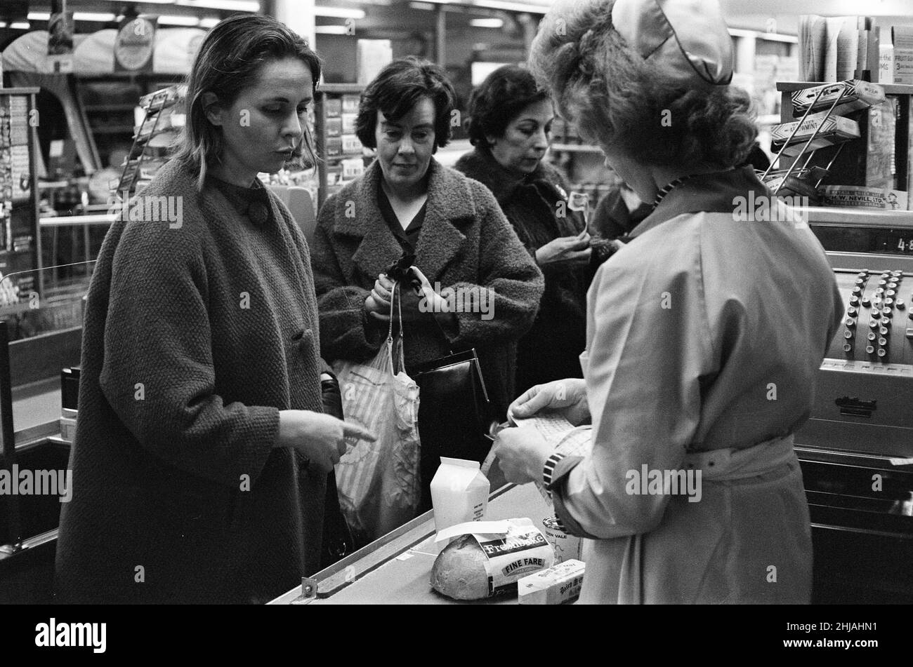 Shopper, Fine Fare Supermarket, Wilton, London, 29th. Oktober 1963. Sammeln Sie Green Shield Briefmarken an der Kasse, nachdem Sie für Waren bezahlt haben. Green Shield Stamps ist ein britisches Verkaufsförderungsprogramm, das Käufer mit Briefmarken belohnt, die eingelöst werden können und zum Kauf von Geschenken aus einem Katalog oder einem angeschlossenen Einzelhändler verwendet werden. Stockfoto