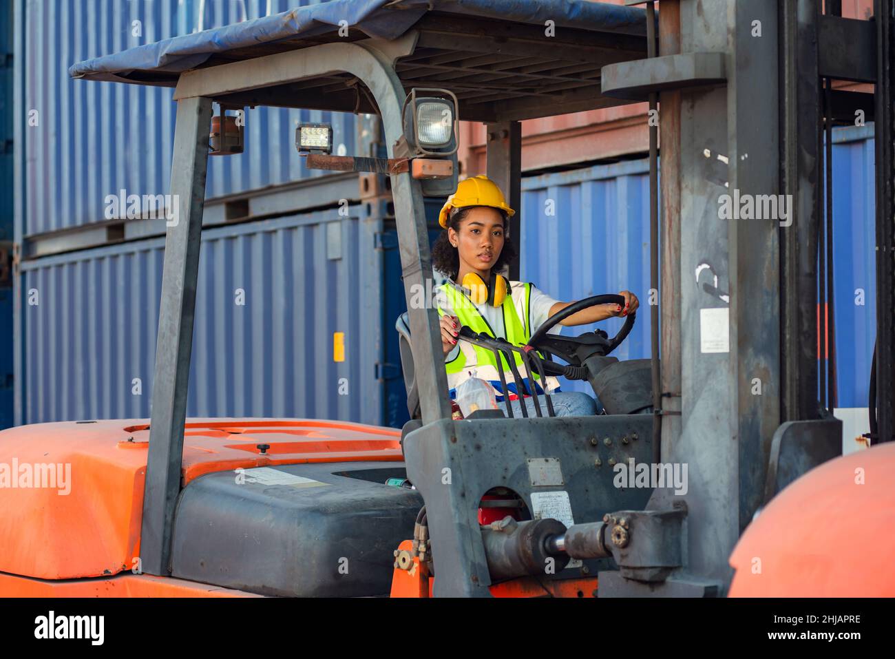 Weibliche Vorarbeiter fährt Gabelstapler auf Versand-Container-Werft. Versand in Docks. Stockfoto