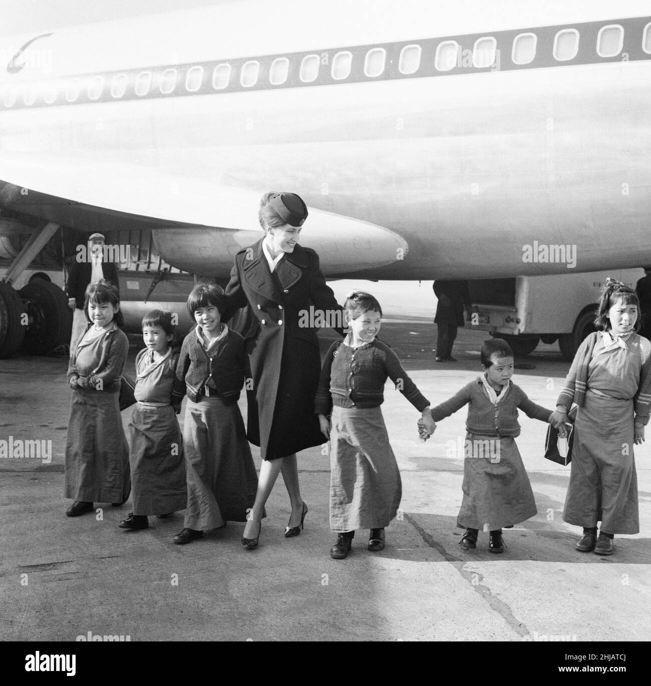21 tibetische Flüchtlingskinder landen am Dienstag, den 26th. Februar 1963, auf dem Flughafen London Heathrow. Ein BOAC Airliner bringt die dreizehn Jungen und acht Mädchen aus einem Flüchtlingslager in Nordindien nach Großbritannien. Viele sind jetzt verwaist, die Kinder sind vor der chinesischen Besatzung und Verfolgung geflohen. Unsere Bildershow ... eine BOAC-Fluggastgeberin führt sechs tibetische Flüchtlinge aus dem Flugzeug. Die Kinder sollen in das Pestalozzi Village for Children in Sedlescombe, East Sussex, verlegt werden, das in den nächsten zehn Jahren ihr neues Zuhause sein wird. Die Gemeinde ist nach dem Schweizer Pädagogen des 18. Jahrhunderts Johann He benannt Stockfoto