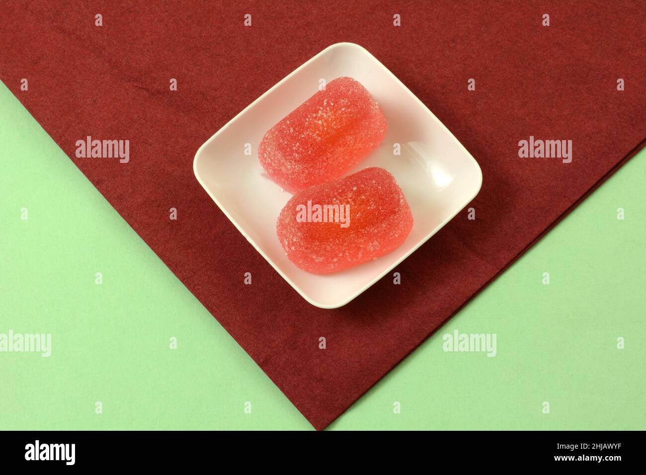 Fruchtgelee Gummy Candy auf weißem Snackteller auf roter Serviette auf grünem Hintergrund Stockfoto