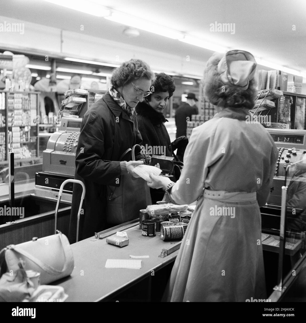 Shopper, Fine Fare Supermarket, Wilton, London, 29th. Oktober 1963. Sammeln Sie Green Shield Briefmarken an der Kasse, nachdem Sie für Waren bezahlt haben. Green Shield Stamps ist ein britisches Verkaufsförderungsprogramm, das Käufer mit Briefmarken belohnt, die eingelöst werden können und zum Kauf von Geschenken aus einem Katalog oder einem angeschlossenen Einzelhändler verwendet werden. Stockfoto