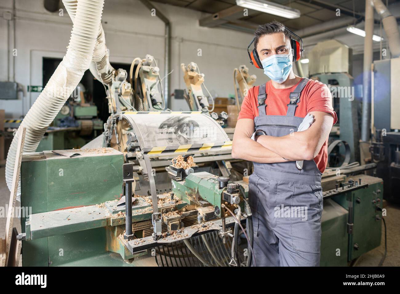 Männlicher Zimmermann in Schutzmaske, der in der Nähe der Holzdrehmaschine steht Stockfoto