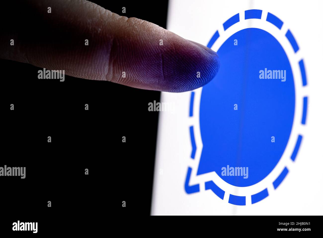 Der Finger greift auf dem Smartphone-Bildschirm nach dem signalverschlüsselten Instant Messaging-Service-Logo. Stockfoto