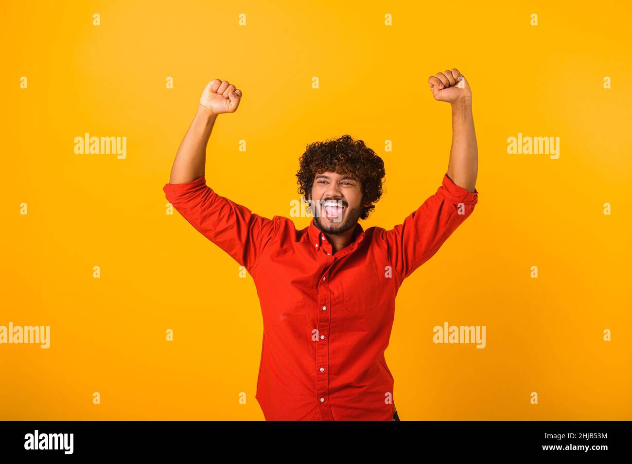 Porträt eines glücklichen schreienden, gut aussehenden bärtigen Mannes, der mit aufgeregtem Gesicht steht und sich über seinen Sieg freut. Innenaufnahme des Studios isoliert auf orangefarbenem Hintergrund Stockfoto