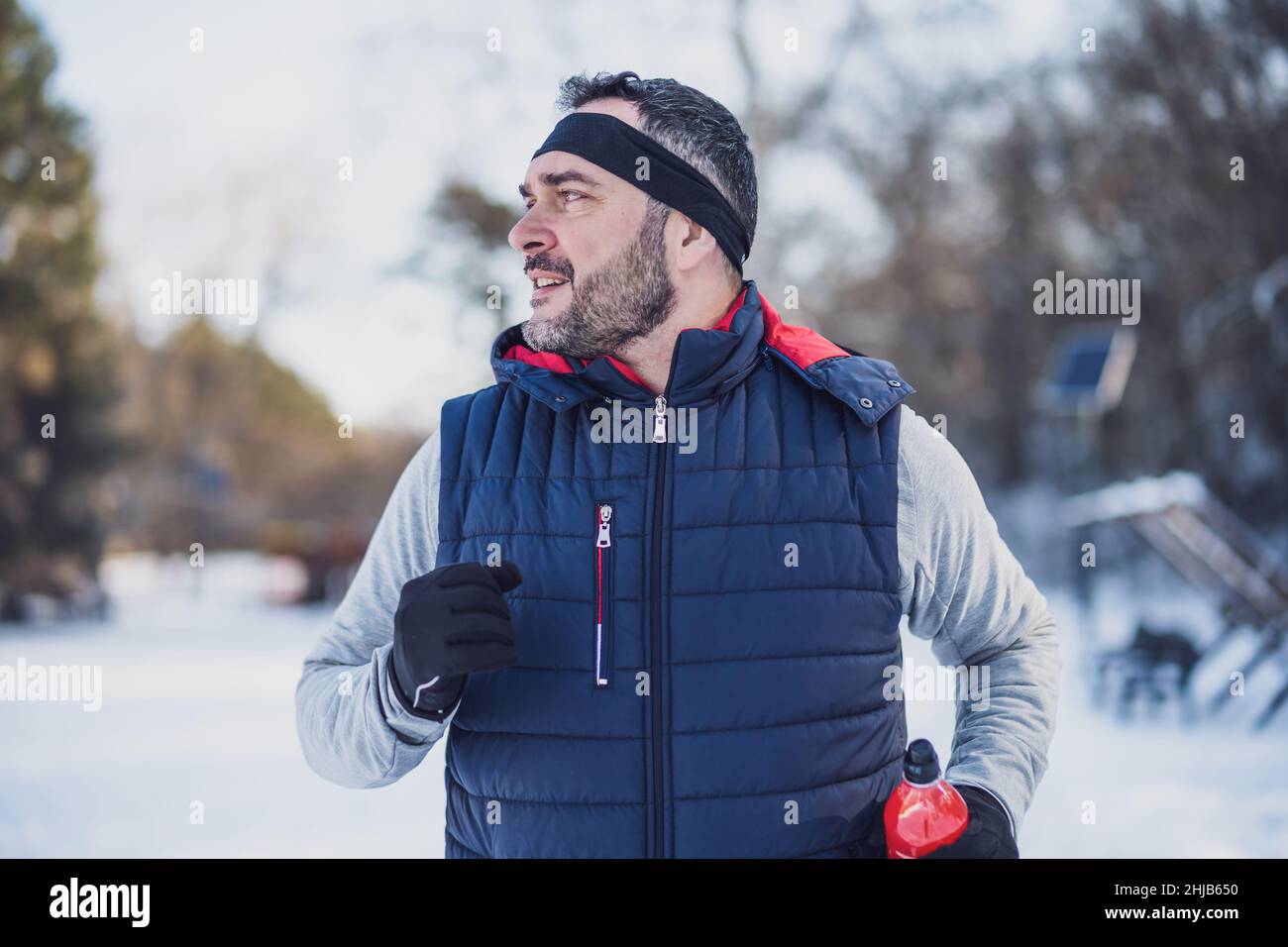 Der Erwachsene Mann trainiert im Winter im Park. Er joggt. Stockfoto