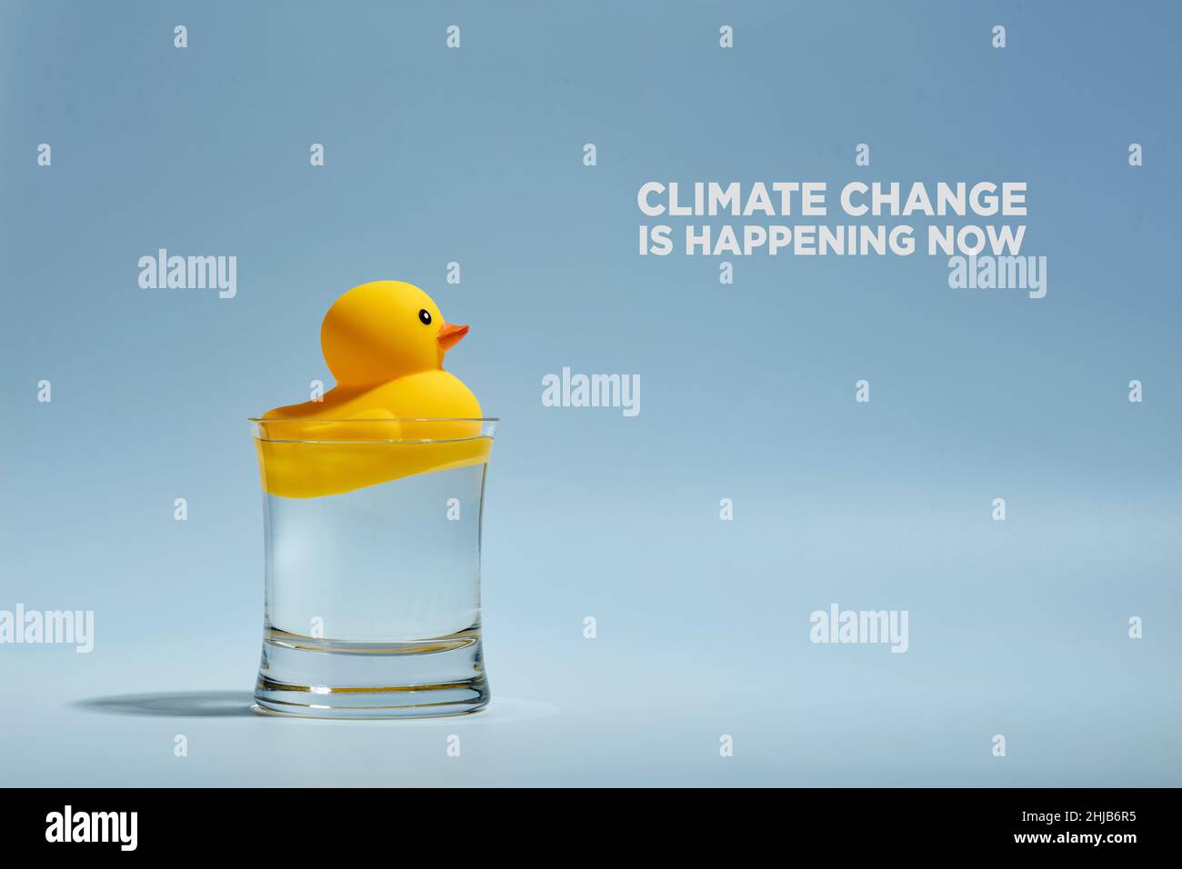 Gelbe Spielzeug-Gummiente schwimmt in einem Glas Wasser mit der Botschaft, dass der Klimawandel jetzt stattfindet. Konzept der globalen Erwärmung und Wasserressourcen. Stockfoto