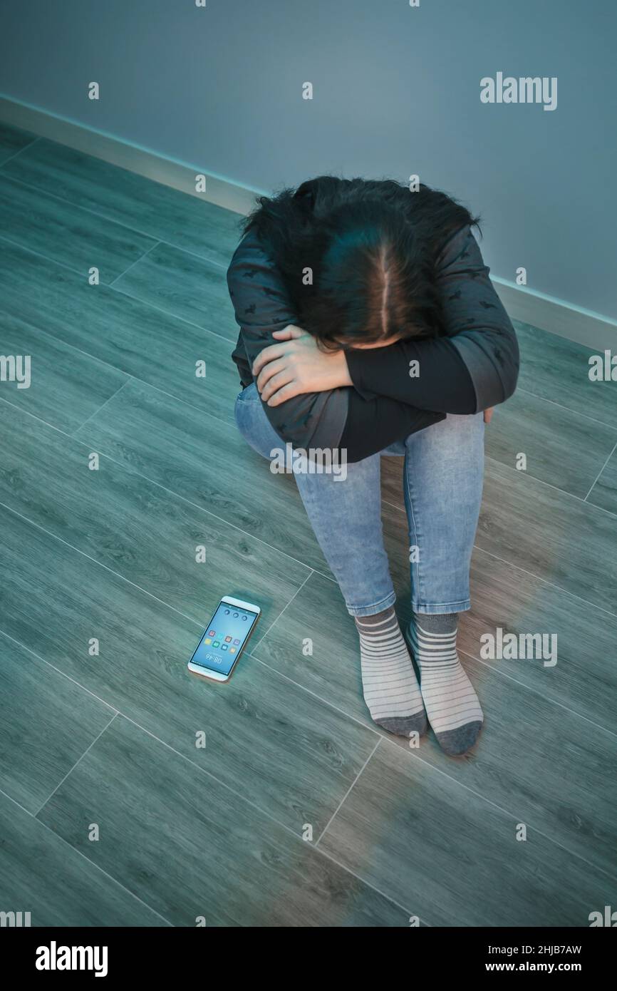 Unverkennbare verzweifelte Frau mit Telefonabhängigkeit, die ihr Gesicht bedeckt Stockfoto