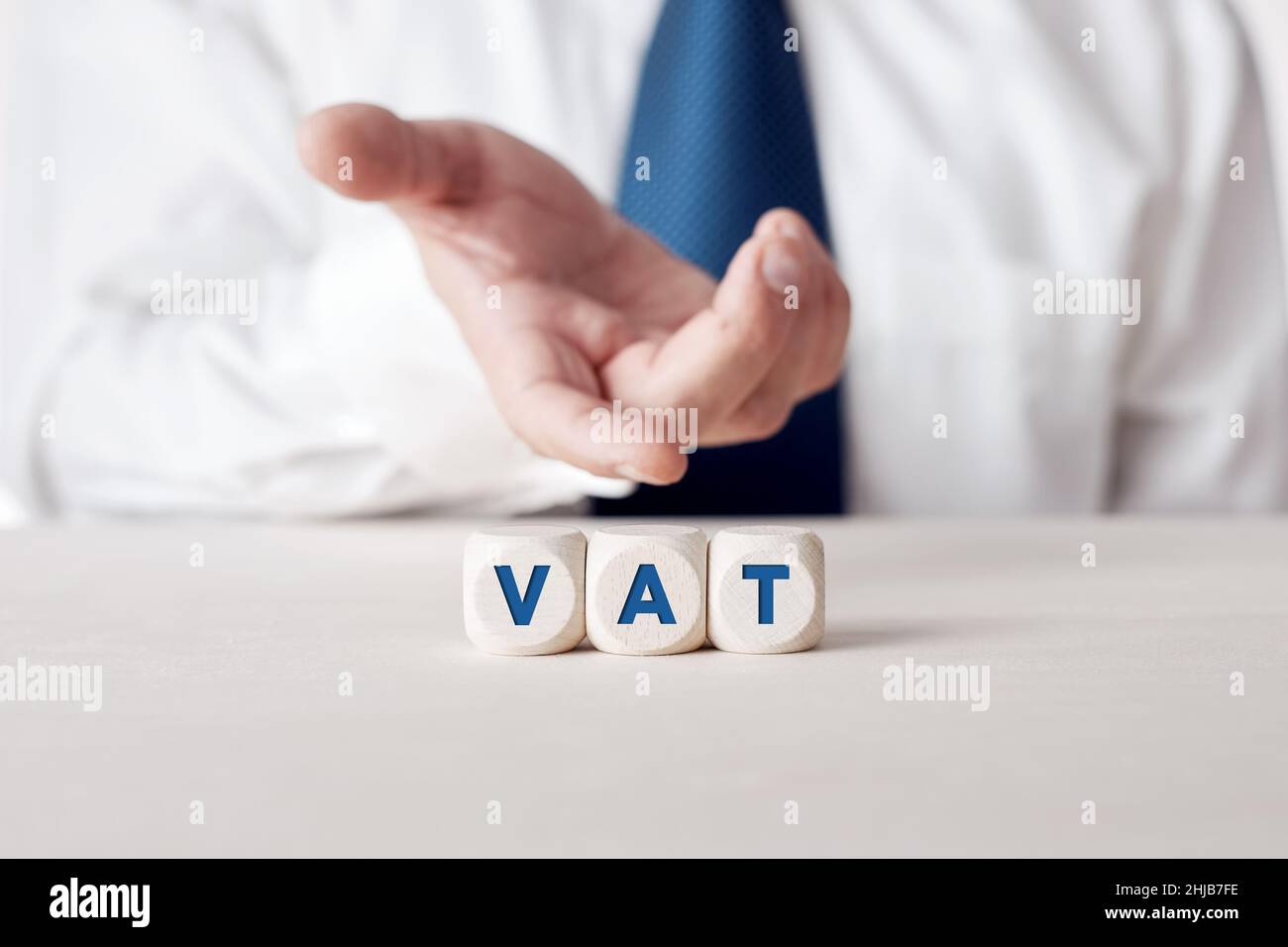 Die Geschäftsfrau zeigt die auf Holzwürfeln geschriebene Abkürzung für „VAT Value Added Tax“. Stockfoto